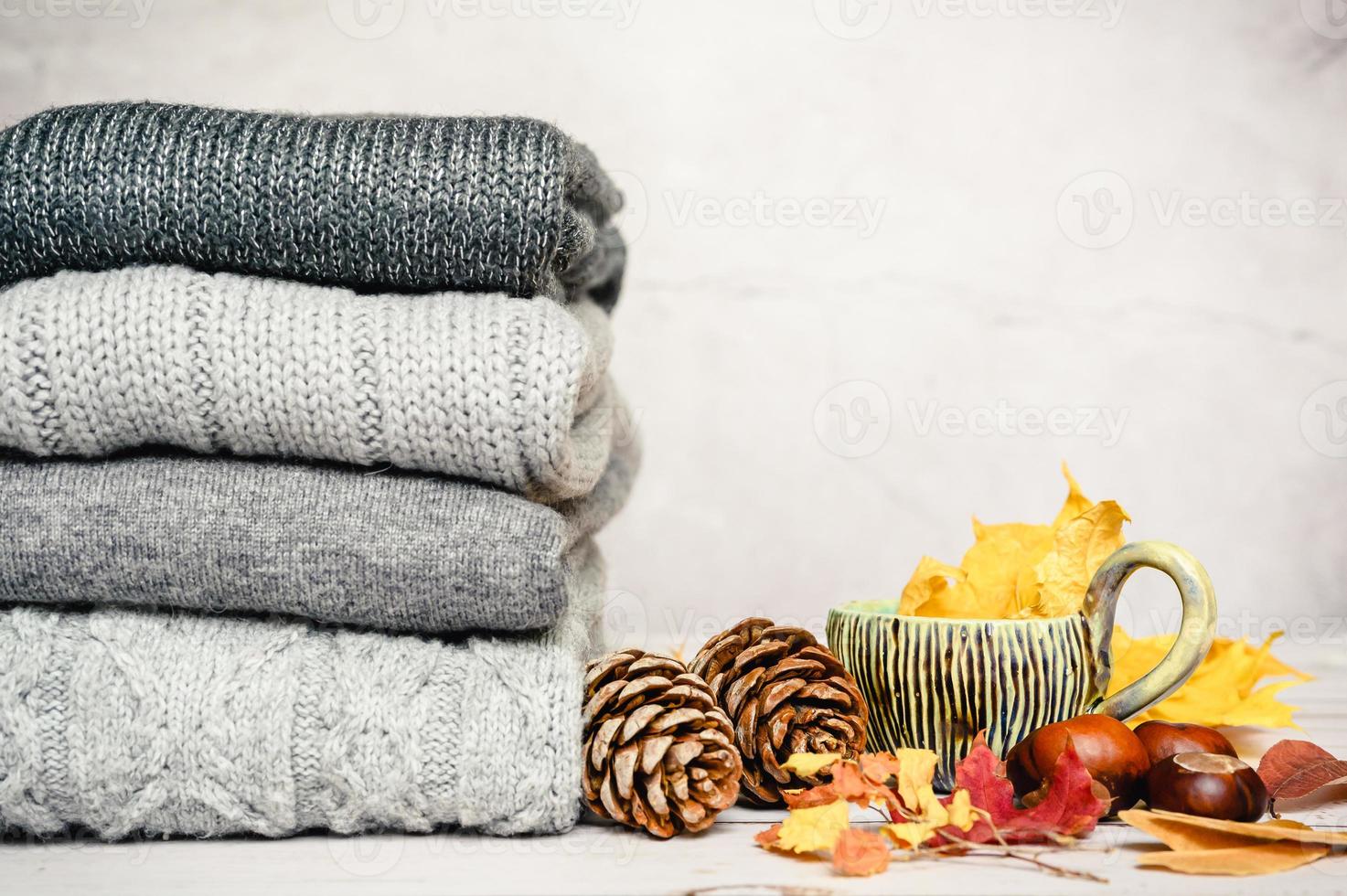 feuilles d'érable jaunes et rouges d'automne sur le fond du pull tricoté confortable gris photo