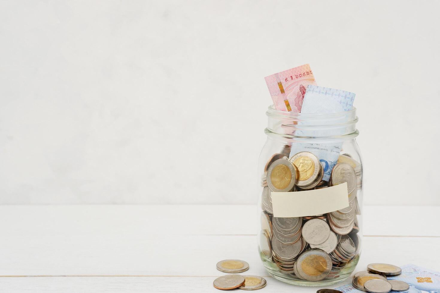 thaïlandais baht billets de banque et pièces de monnaie dans une verre pot. affaires et la finance concept. photo