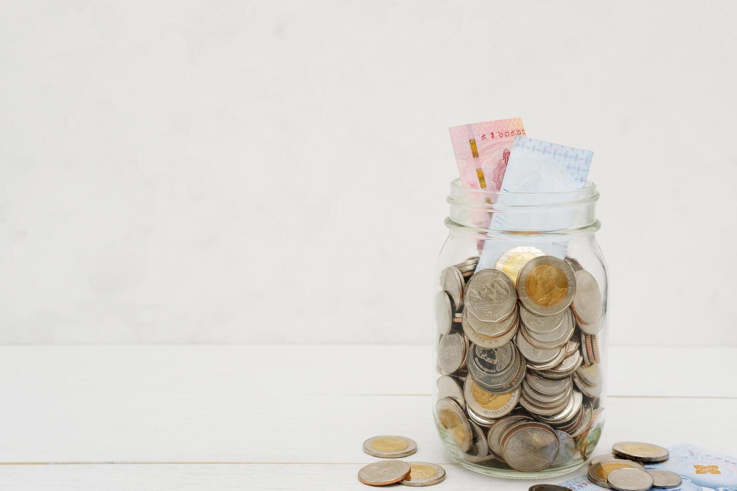 thaïlandais baht billets de banque et pièces de monnaie dans une verre pot. affaires et la finance concept. photo