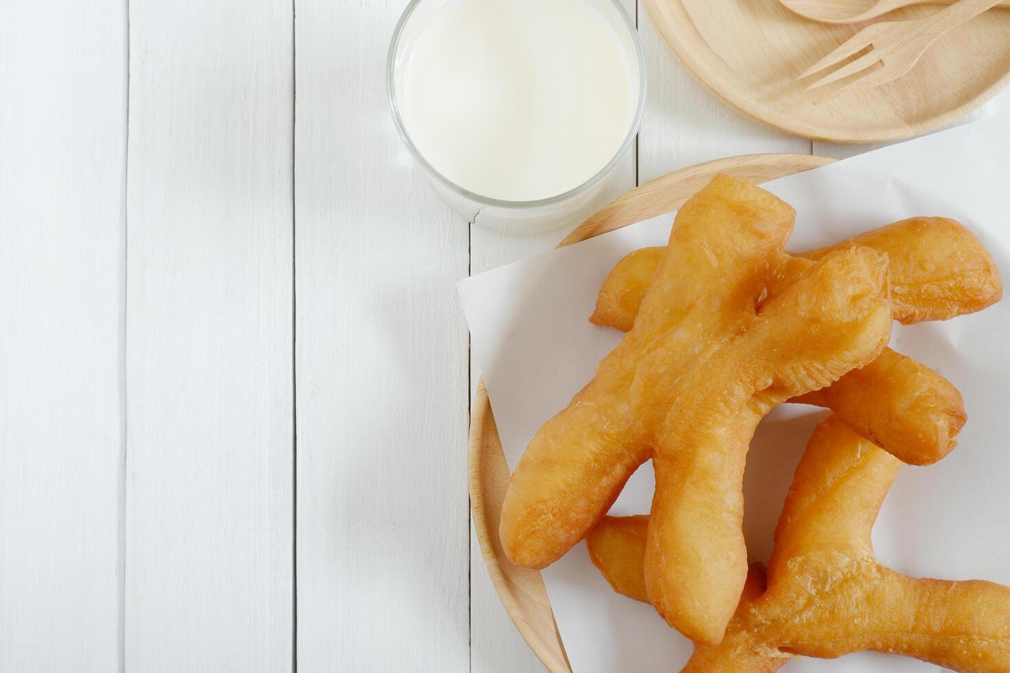 Pennsylvanie tong aller, thaïlandais style chinois crullers dans en bois assiette sur blanc en bois Contexte. Haut vue avec copie espace. photo