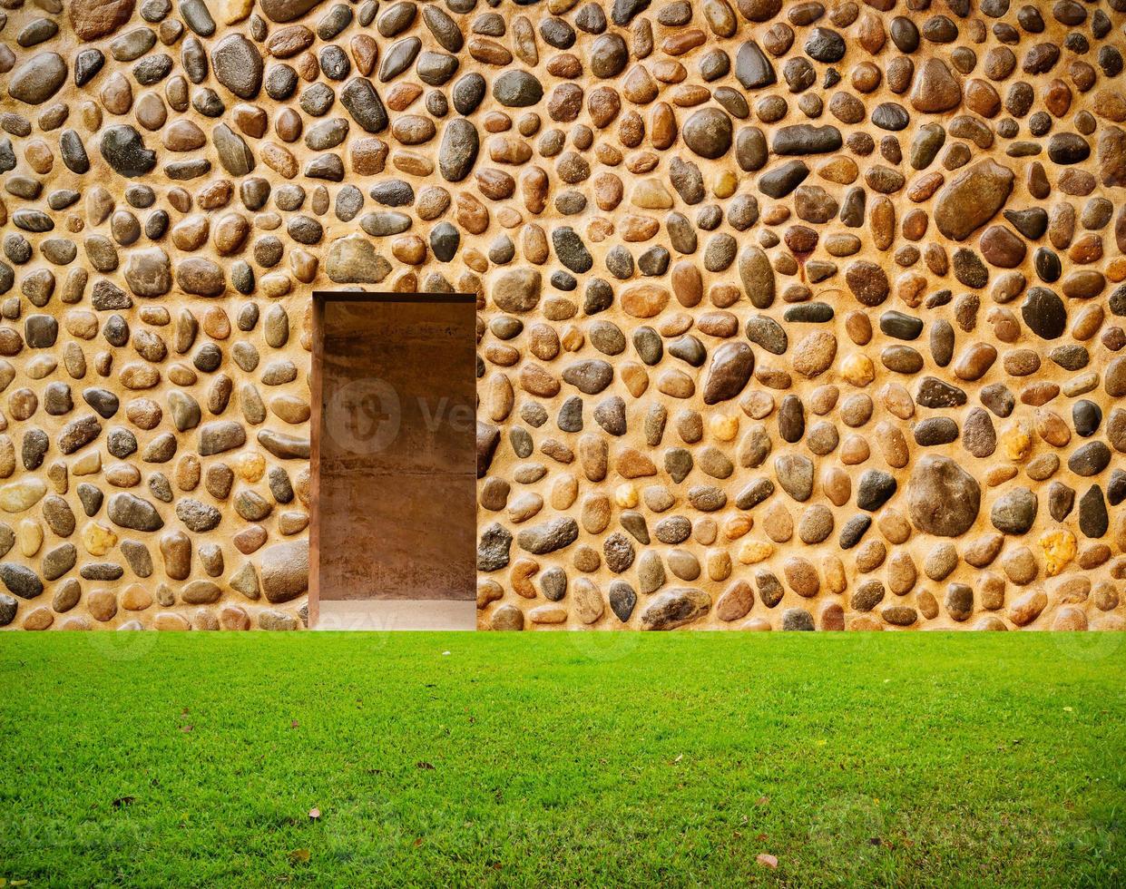 mur de pierre avec porte et sol en gazon devant photo