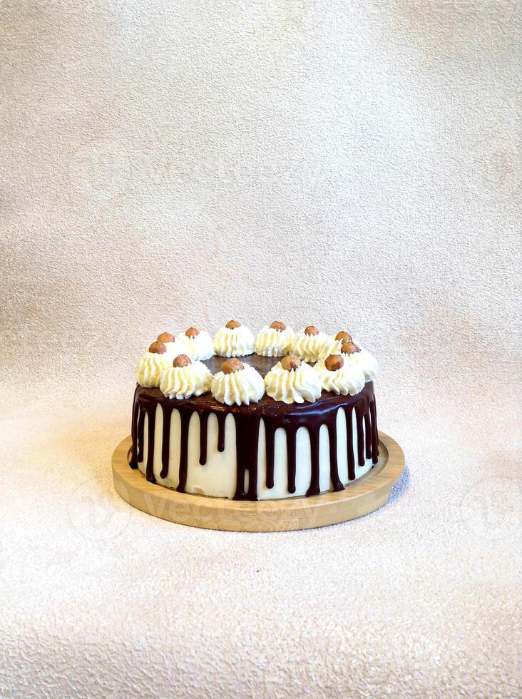 anniversaire blanc et marron Chocolat gâteau avec noisettes sur une en bois assiette sur une lumière Contexte photo