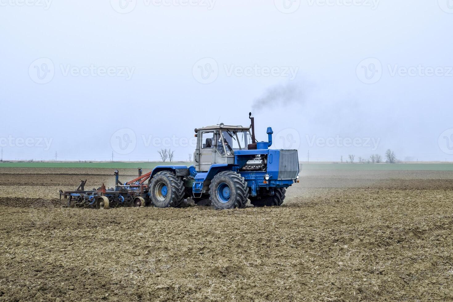 luxuriant et desserrer le sol sur le champ avant semis. le tracteur charrues une champ avec une charrue photo