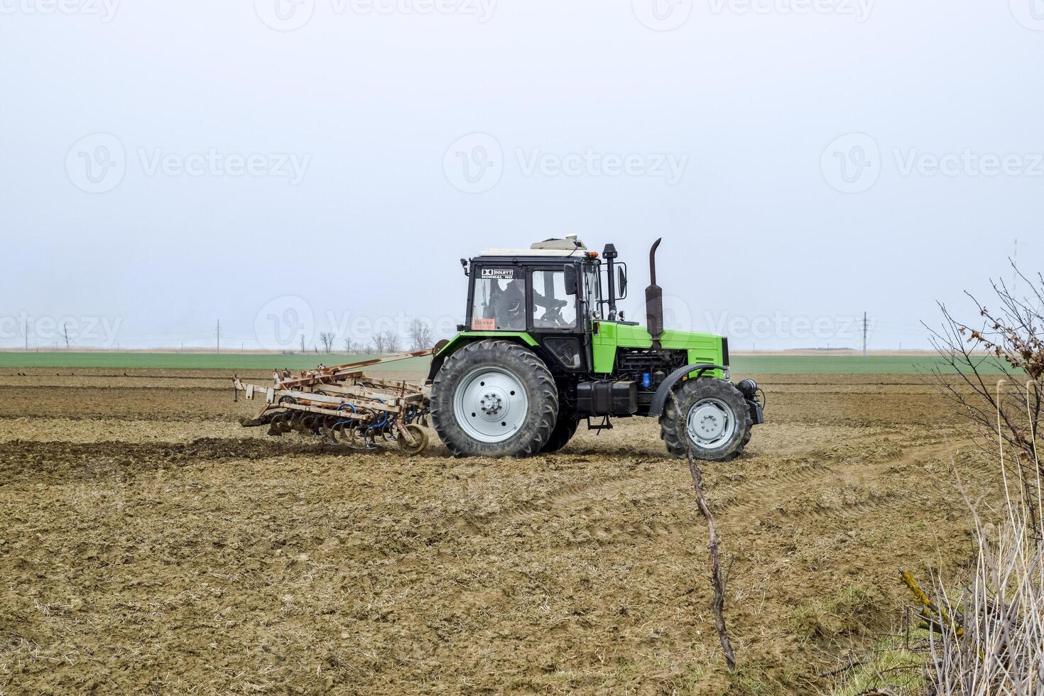 luxuriant et desserrer le sol sur le champ avant semis. le tracteur charrues une champ avec une charrue photo