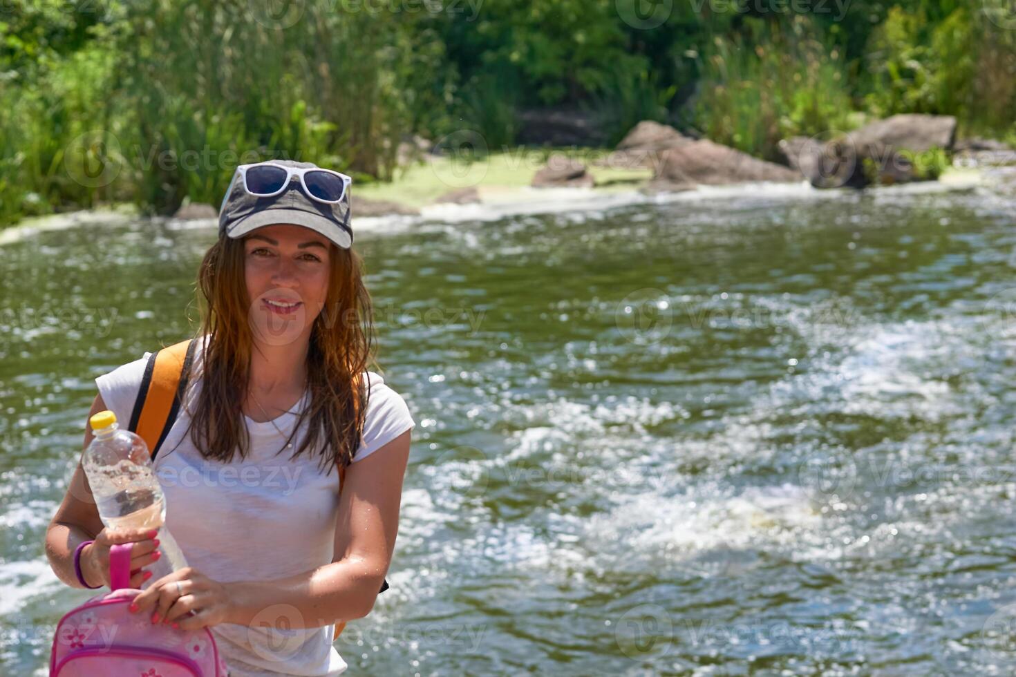 Jeune femme touristique avec avec une bouteille de minéral banque d'eau de une rapide rivière photo