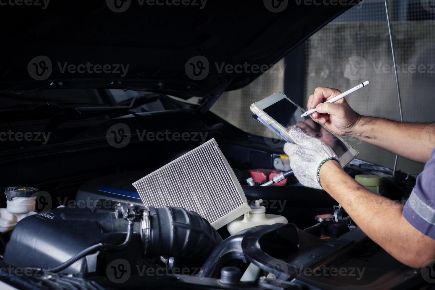 le mécanicien chèques le moteur en utilisant tablette ordinateur technologie. Achevée avec clé outil auto mécanicien travail dans le garage. réparation service. photo