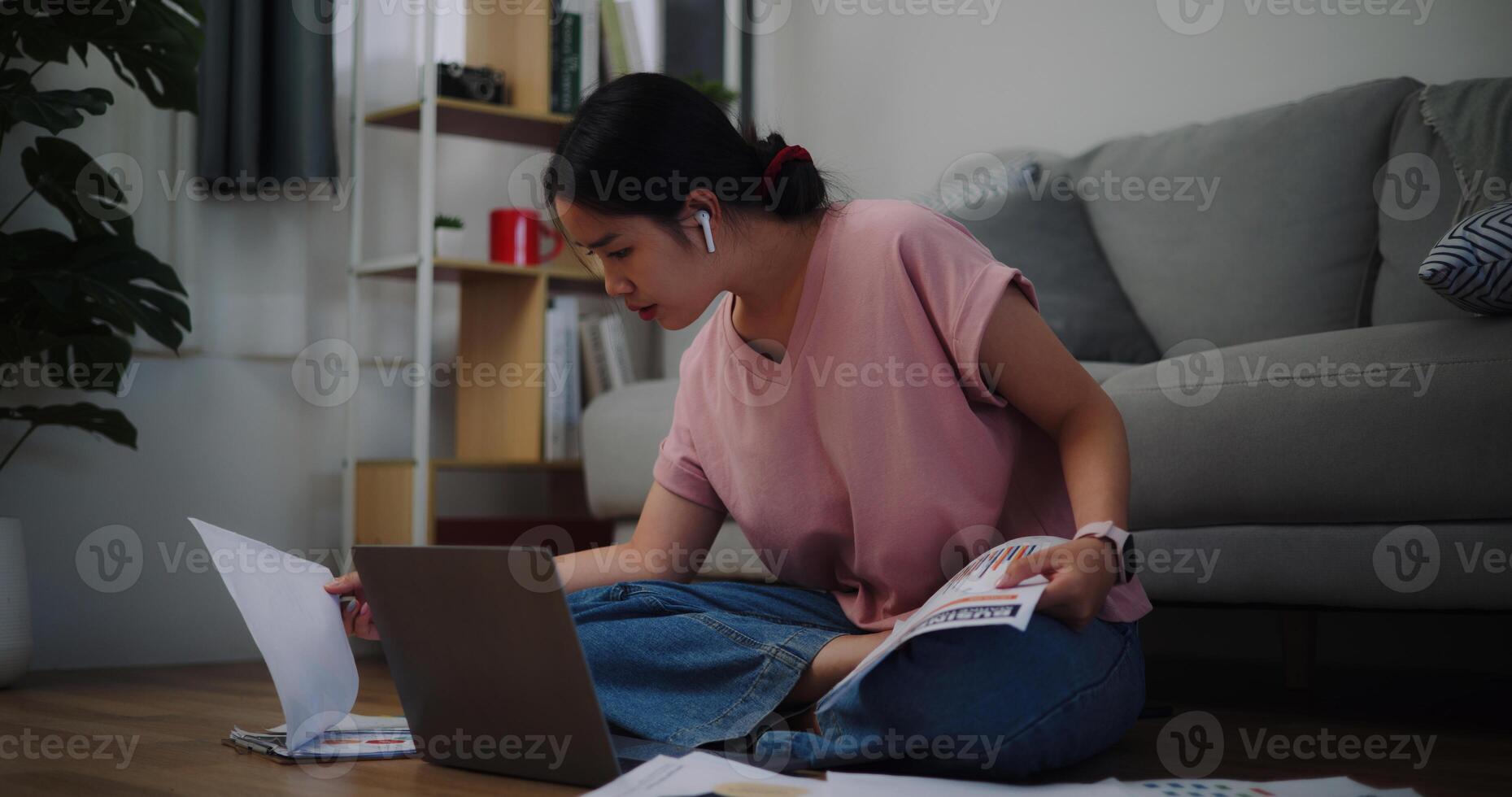 portrait de Jeune femme séance sur le sol travail avec une portable et vérification Document de travail à Accueil bureau. photo