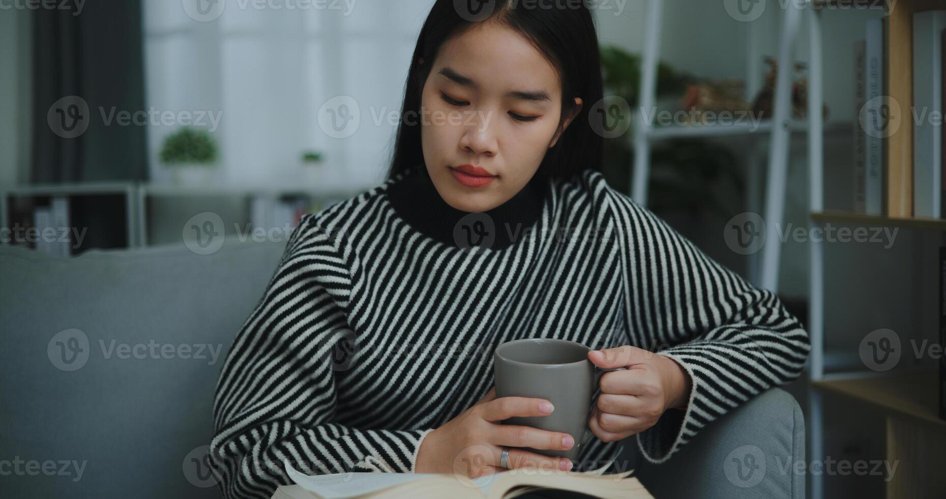 portrait de content Jeune asiatique femme en buvant Matin café ou thé et en train de lire dans vivant pièce à Accueil sur fin de semaine. loisir et style de vie, gratuit temps photo