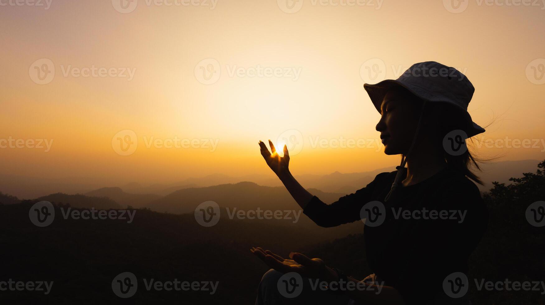 silhuette jeune femme priant sur la montagne, les bras tendus observant un beau lever de soleil dramatique. photo