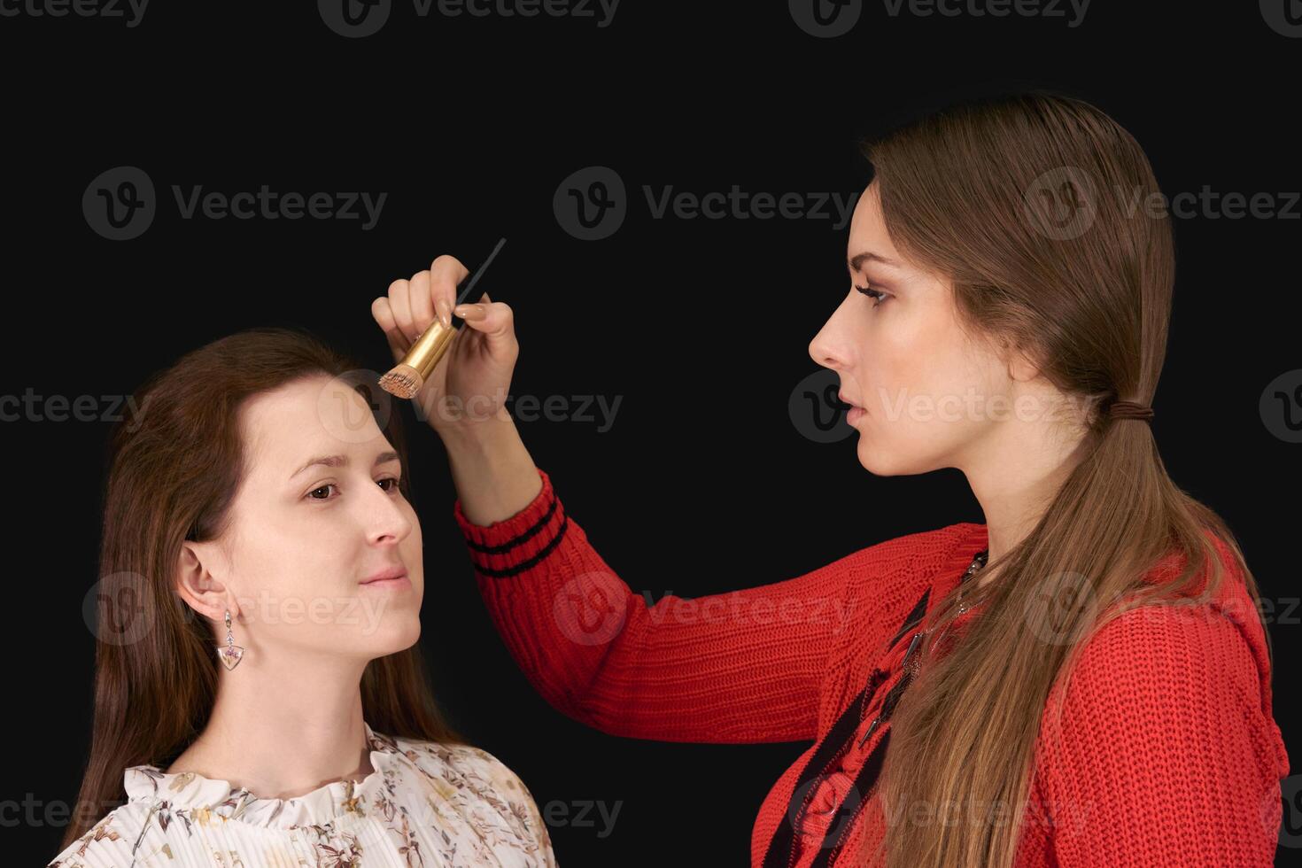 femelle maquillage artiste s'applique produits de beauté à modèle sur foncé Contexte photo