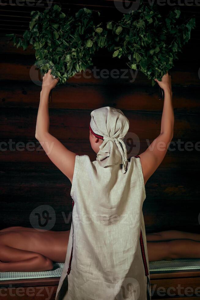 en utilisant de une baignoire balais dans une traditionnel vapeur sauna banya photo