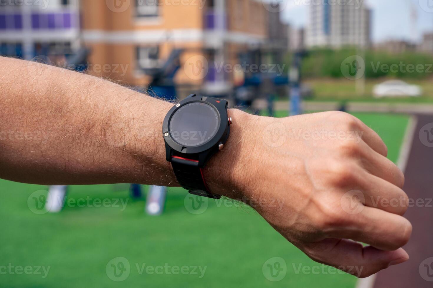 Regardez à une montre intelligente sur une homme main contre le Contexte de Extérieur exercice équipement photo