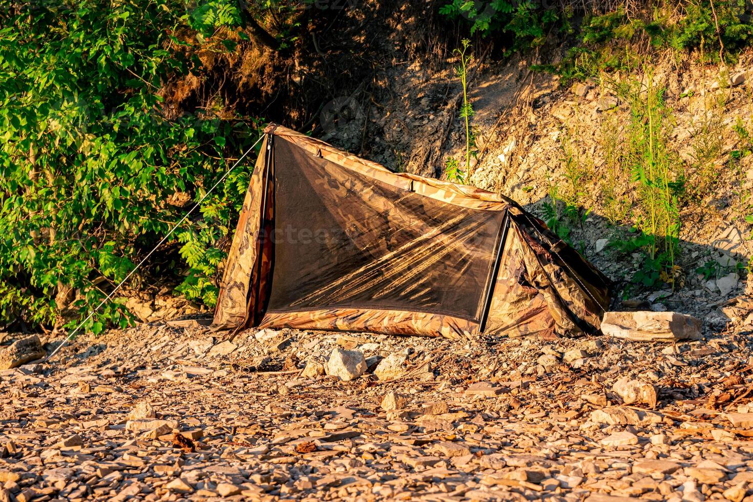 une randonnée camp sur une rocheux rive, petit une personne tente photo