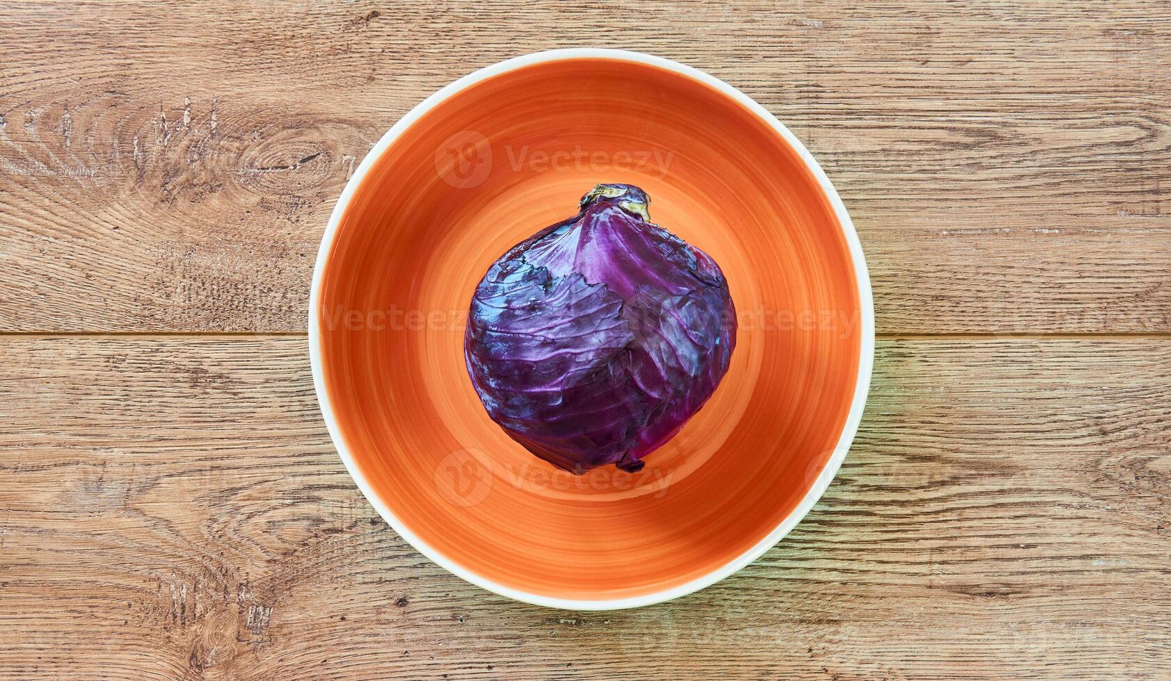 violet tête de rouge chou sur une Orange assiette sur une en bois dessus de la table photo