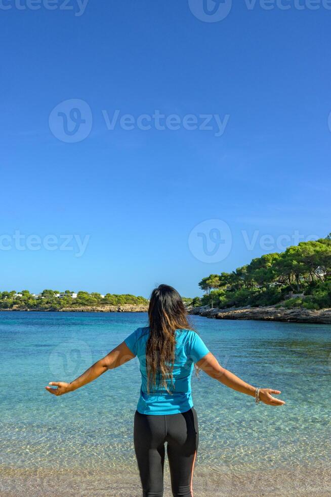 latina femme, vu de derrière, dans tenue de sport, à la recherche à le mer, respiration profondément. photo