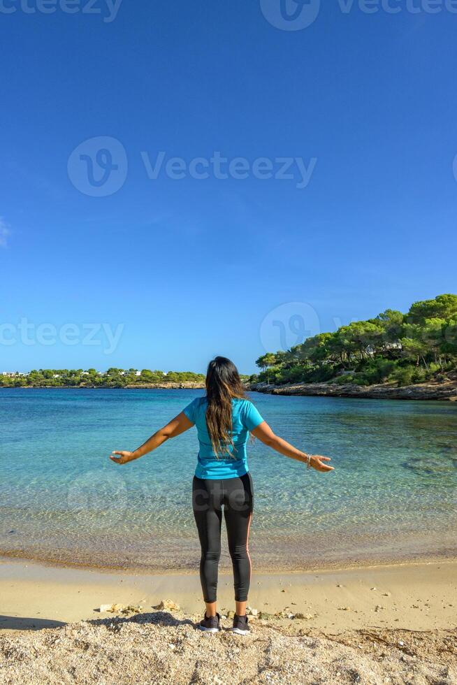 latina femme, sur le rive de le plage à la recherche à le mer respiration profondément photo