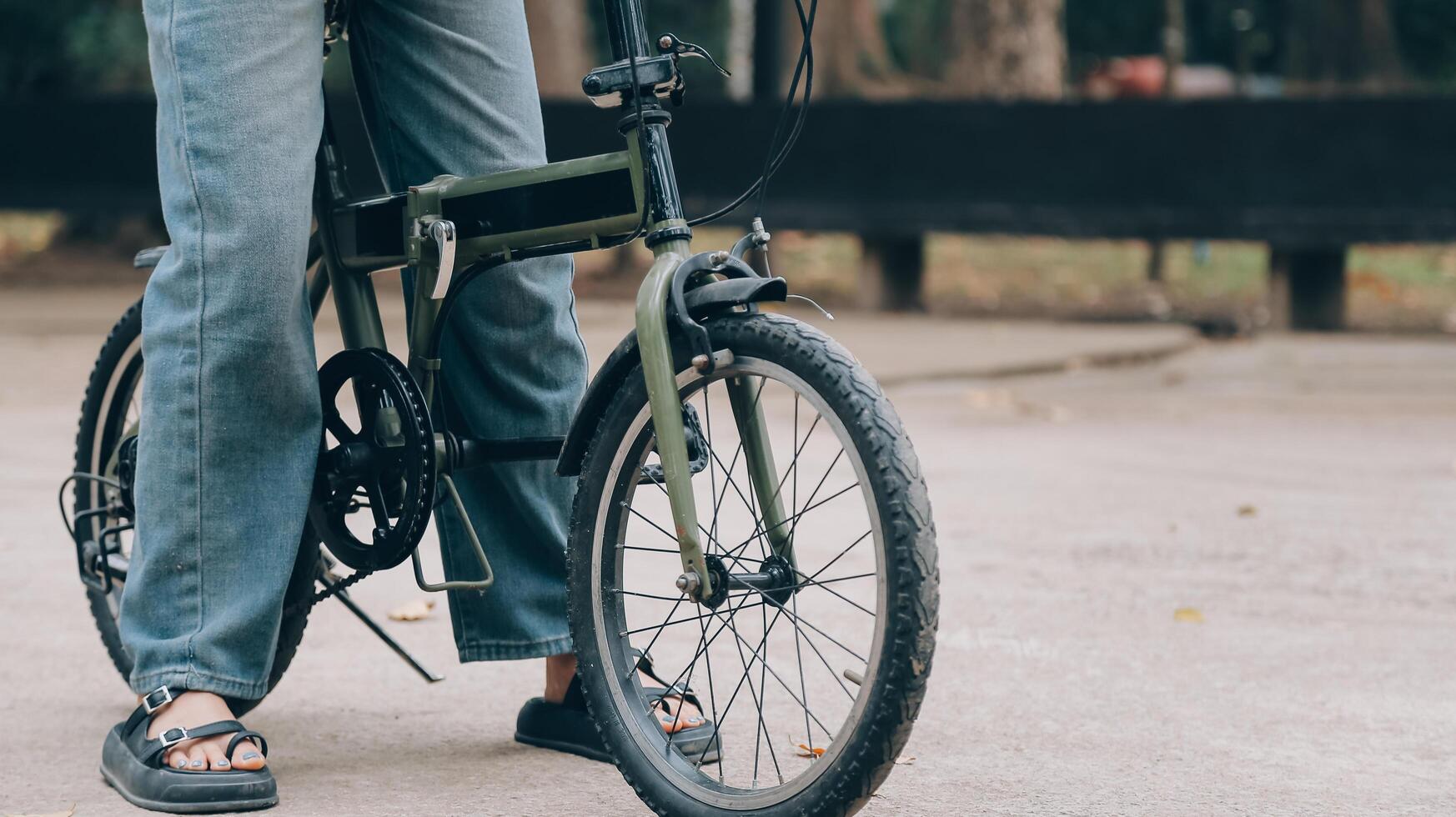 content Jeune asiatique femme tandis que équitation une vélo dans une ville parc. elle sourit en utilisant le vélo de transport. écologiquement amical concept. photo