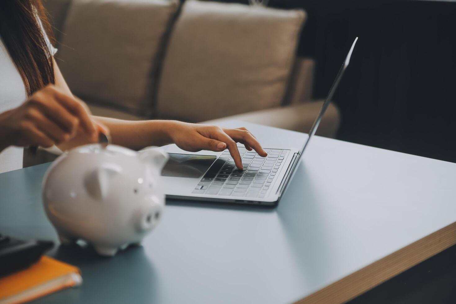 Jeune asiatique femme économie pour retraite économie argent par une porcin banque et prise Remarques sur carnet de notes, des économies concept. photo