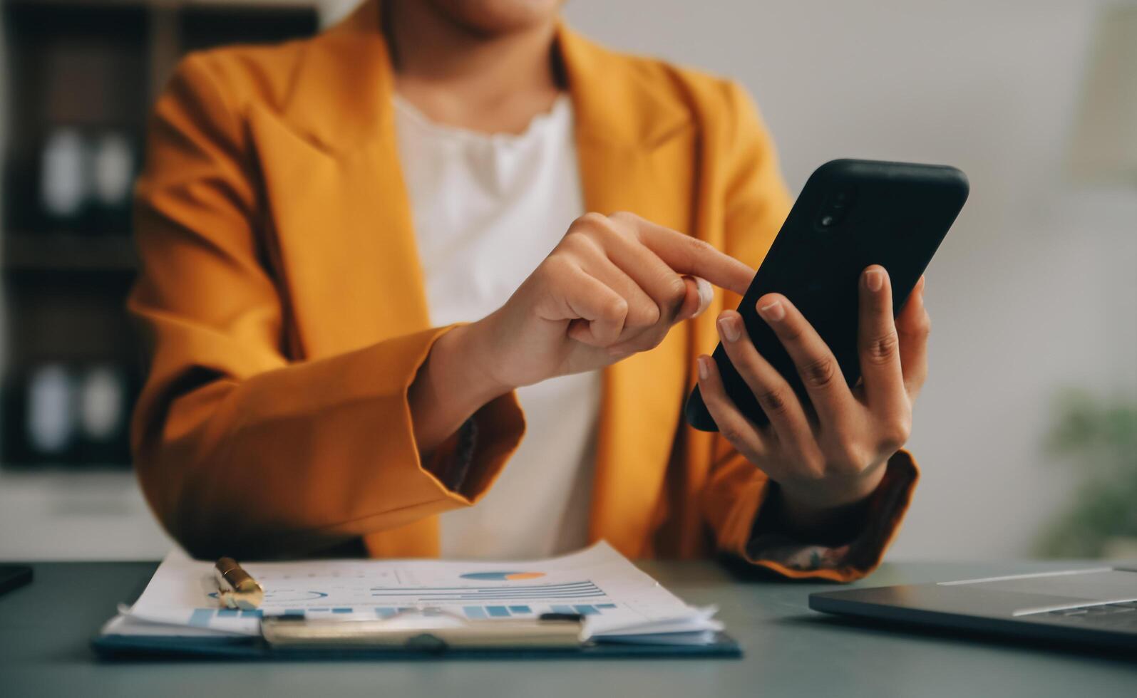 femme d'affaires asiatique en costume formel au bureau heureuse et joyeuse lors de l'utilisation d'un smartphone et du travail photo