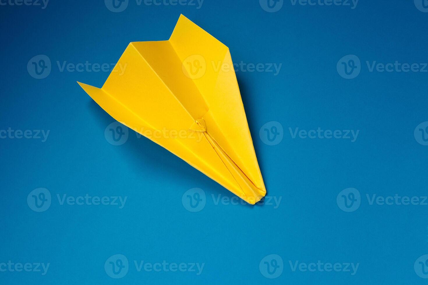 Jaune origami avion sur une bleu Contexte. photo