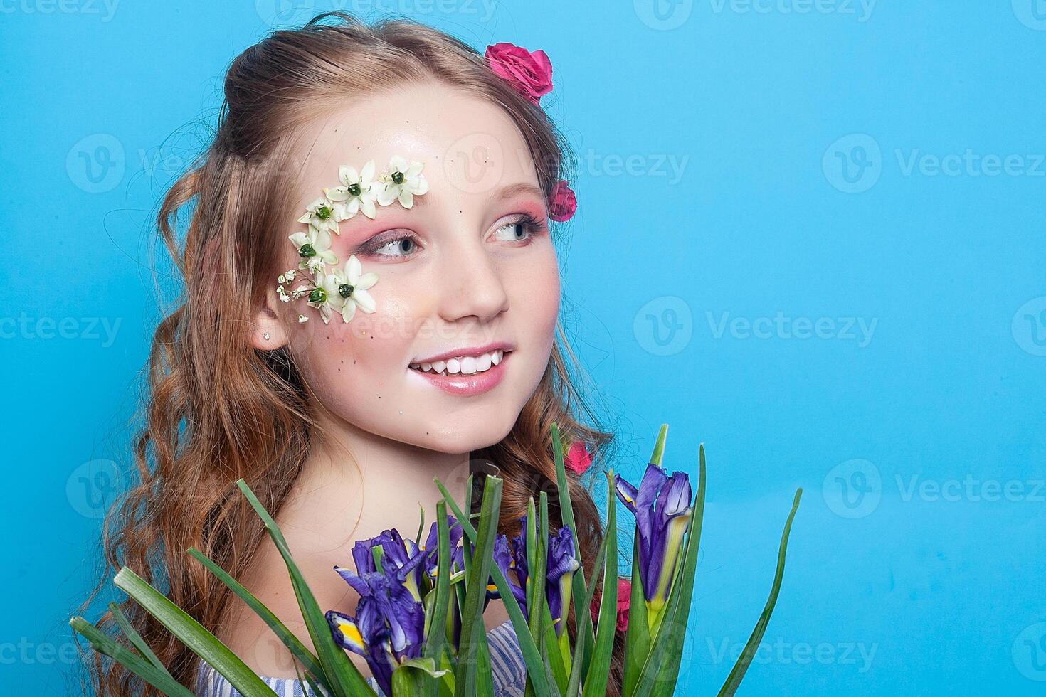 positif fille. peu fille avec marguerites dans sa mains sur une bleu Contexte. photo