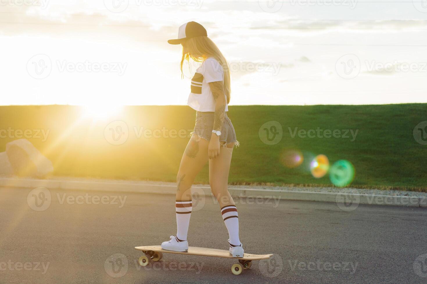 portrait de une branché Jeune fille souriant avec une longboard à le coucher du soleil. photo