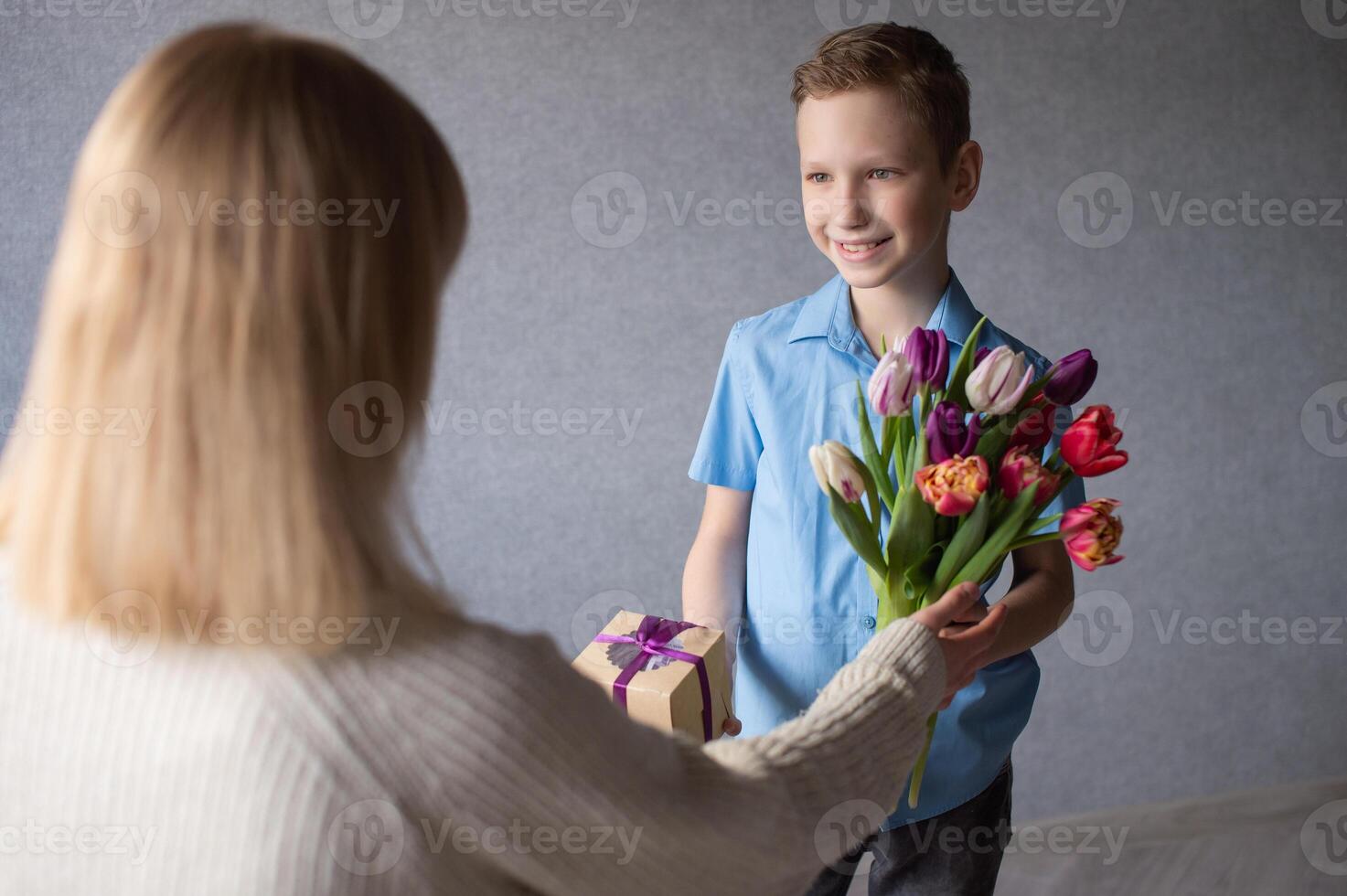 mignonne garçon souriant et à la recherche à maman, donnant fleurs et cadeaux pour de la mère journée photo