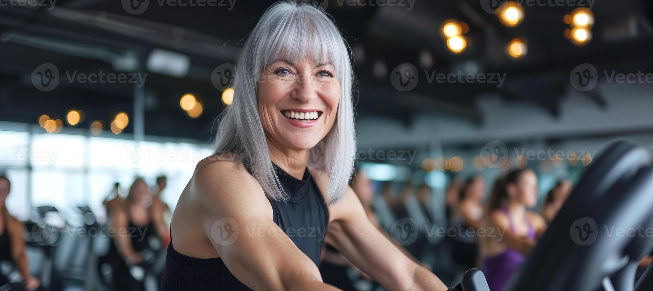 ai généré actif Sénior femme avec gris cheveux exercice sur une Stationnaire bicyclette avec groupe de gens dans Gym photo