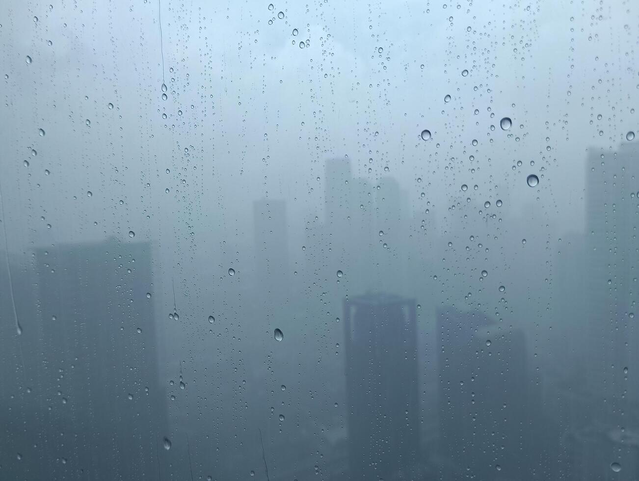 floue vue avec l'eau gouttes sur le fenêtre de le gratte-ciel bâtiments photo