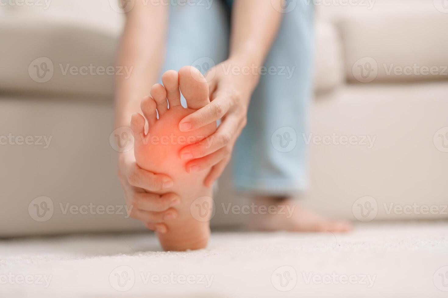 femme ayant pieds nus douleur pendant séance sur canapé à maison. pied mal dû à plantaire fasciite et veille longue durée. santé et médical concept photo