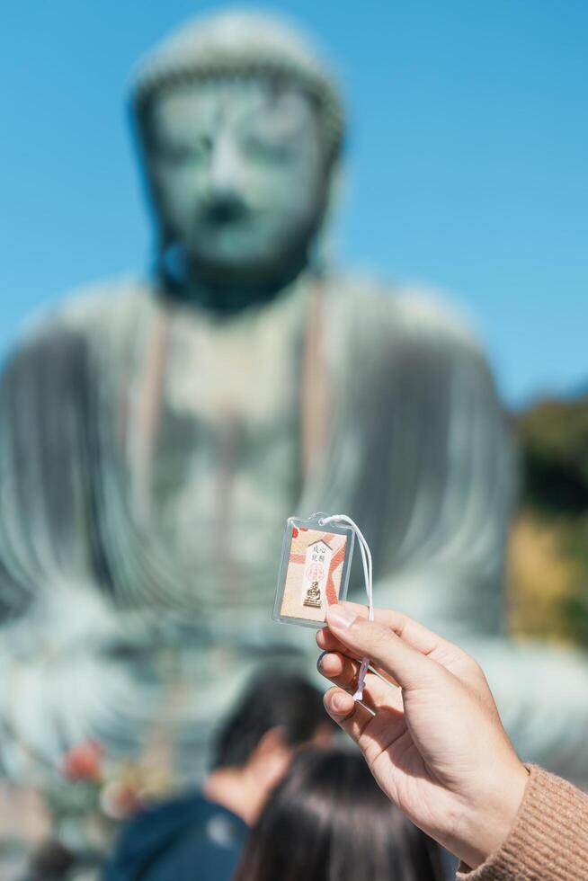 touristique spectacle Japon souvenir Omamori, Japonais texte cette signifier chanceux charme. voyageur tourisme le génial Bouddha statue. Kamakura, Kanagawa, Japon, 16 novembre 2023 photo