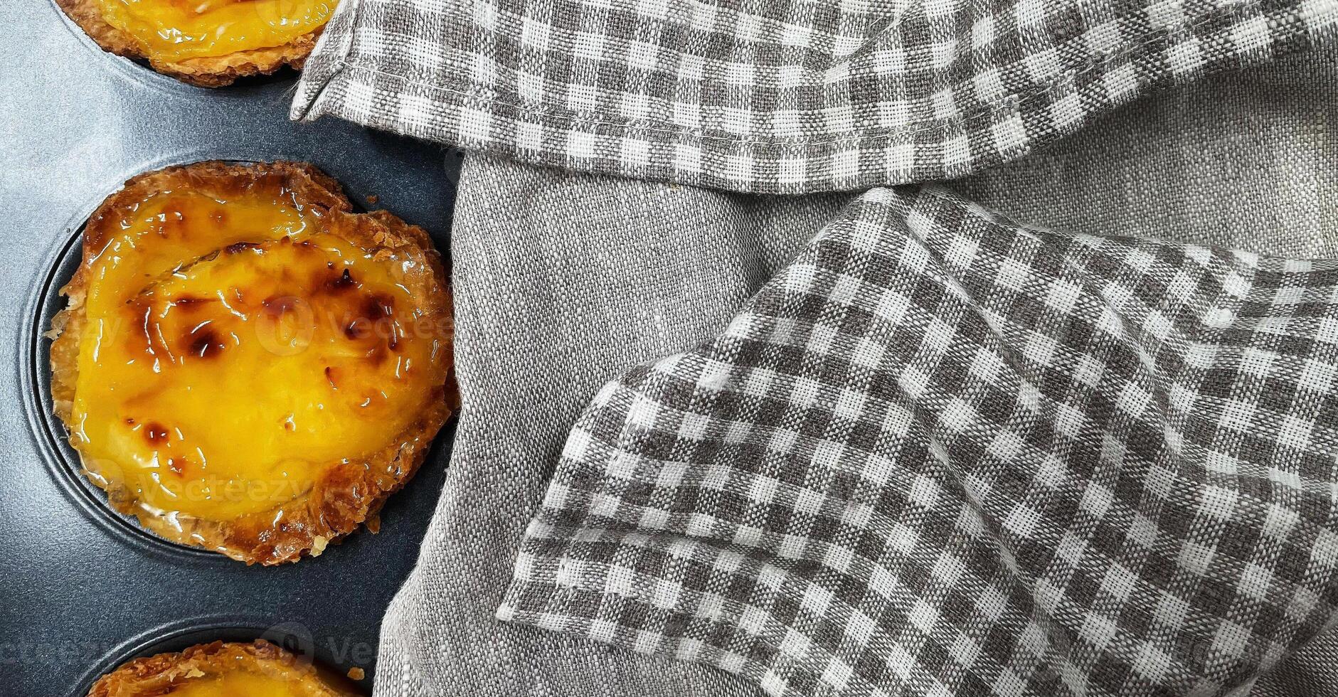 beaucoup de fraîchement cuit pastel de nata ou Portugais Oeuf Tarte desserts dans une cuisson plat. pastel de Belme est une petit tarte avec une croustillant bouffée Pâtisserie croûte et une Crème remplissage. petit petit gâteau. photo