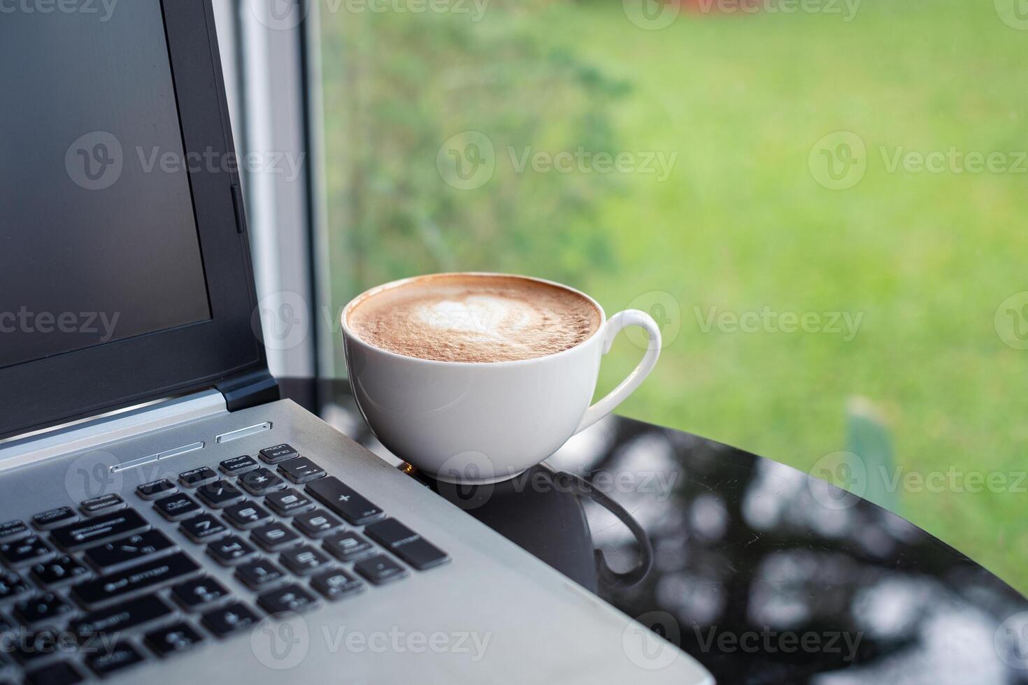 chaud latté café avec moderne portable sur verre table photo