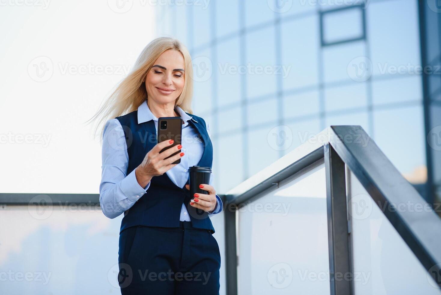 magnifique femme Aller à travail avec café en marchant près Bureau bâtiment. portrait de réussi affaires femme en portant tasse de chaud boire. photo