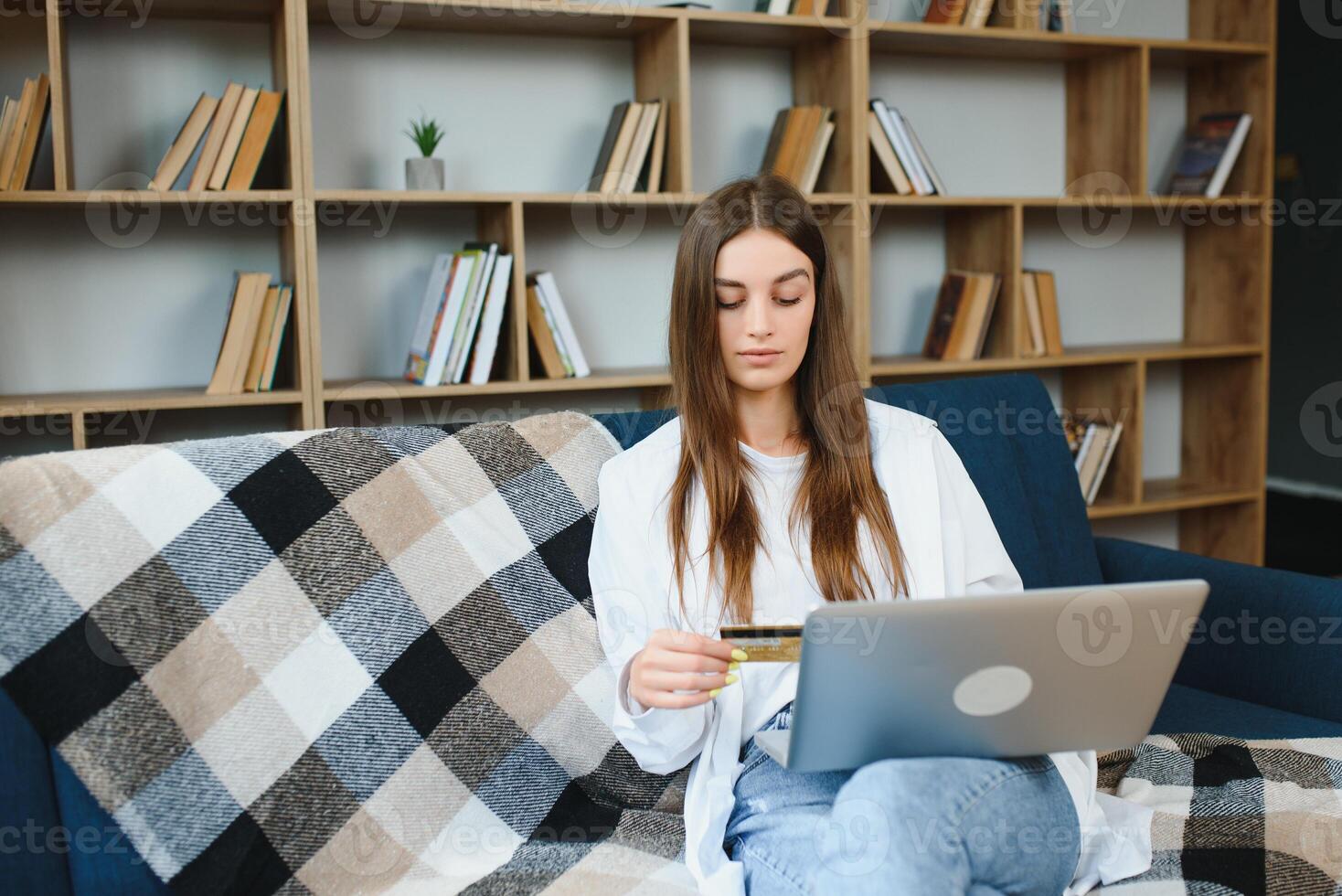 en ligne magasin. content fille Faire achats via l'Internet en utilisant portable et crédit carte, séance sur canapé, fond photo