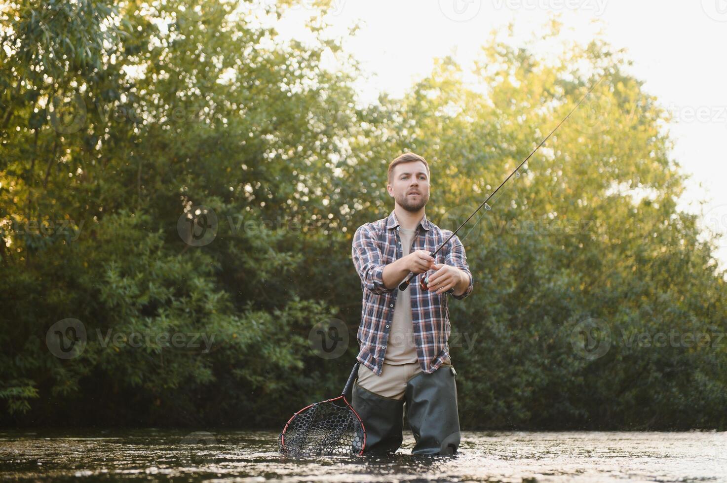 pêcheur captures une truite sur le rivière dans été photo