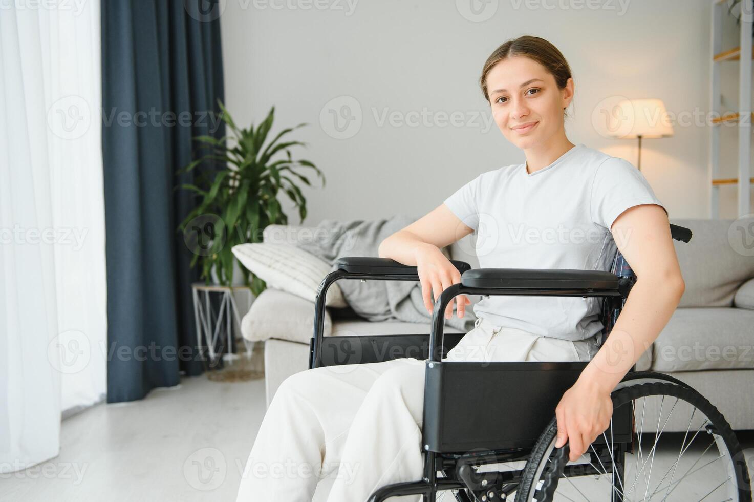 Jeune femme dans fauteuil roulant à Accueil dans vivant chambre. photo