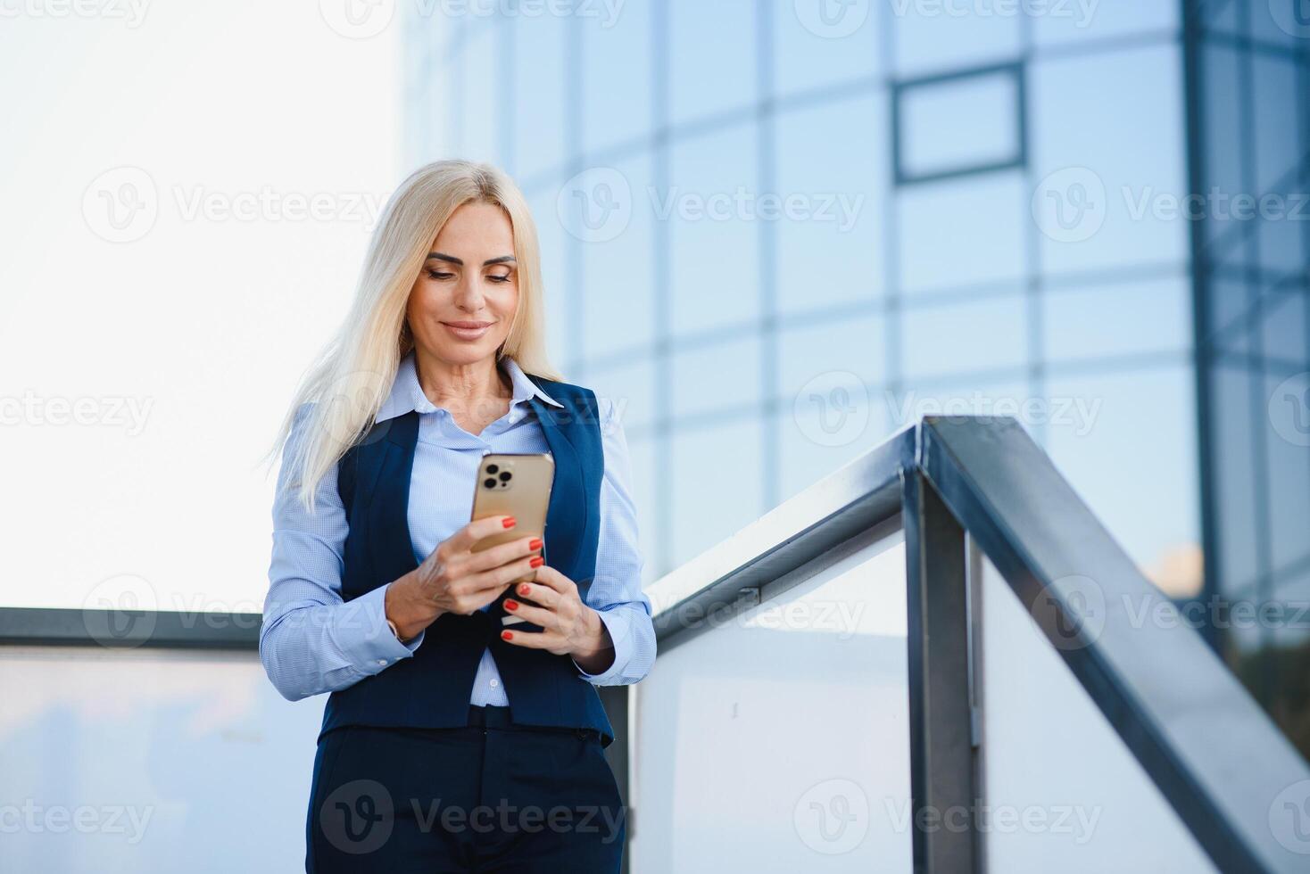 femme d'affaires avec téléphone près du bureau. portrait d'une belle femme souriante dans des vêtements de bureau de mode parlant au téléphone tout en se tenant à l'extérieur. communication téléphonique. image de haute qualité. photo