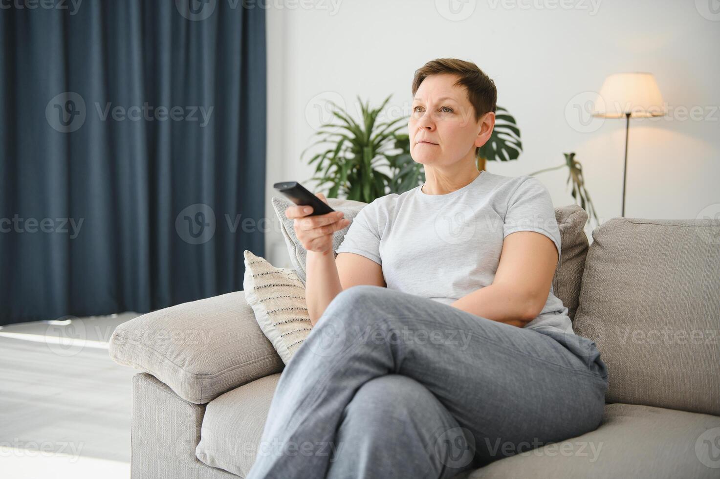 portrait de content plus âgée femme en changeant canal sur télévision. photo