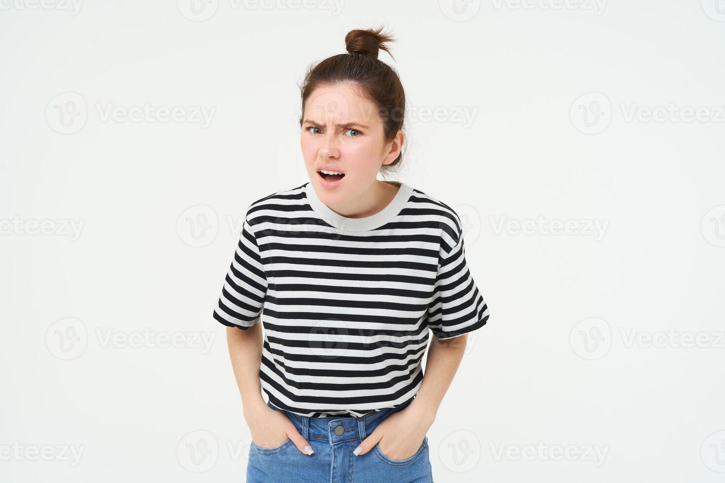 portrait de Jeune femme avec choqué, en colère visage expression, entendre quelque chose décevant, spectacles négatif, frustré réaction, permanent plus de blanc Contexte photo