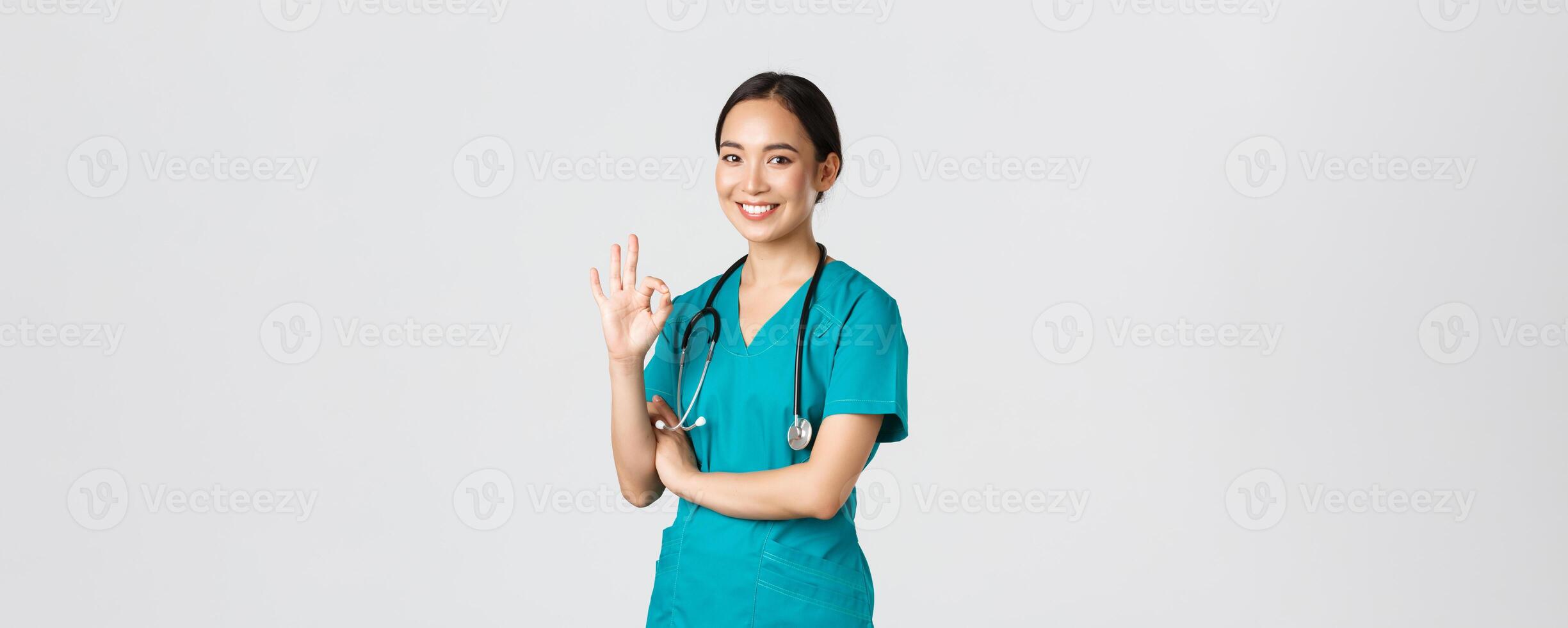 COVID-19 [feminine, soins de santé ouvriers, pandémie concept. sur de soi professionnel asiatique médecin, femelle médecin dans gommages, montrant d'accord geste, garantie qualité de prestations de service dans hôpital, approuver et se mettre d'accord photo