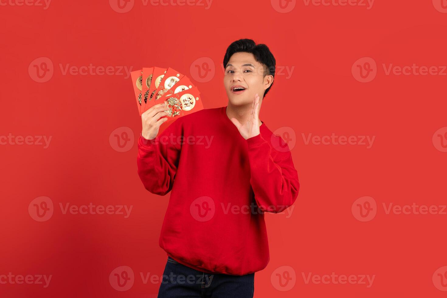 excité Beau asiatique homme en portant rouge enveloppes isolé rouge Contexte photo