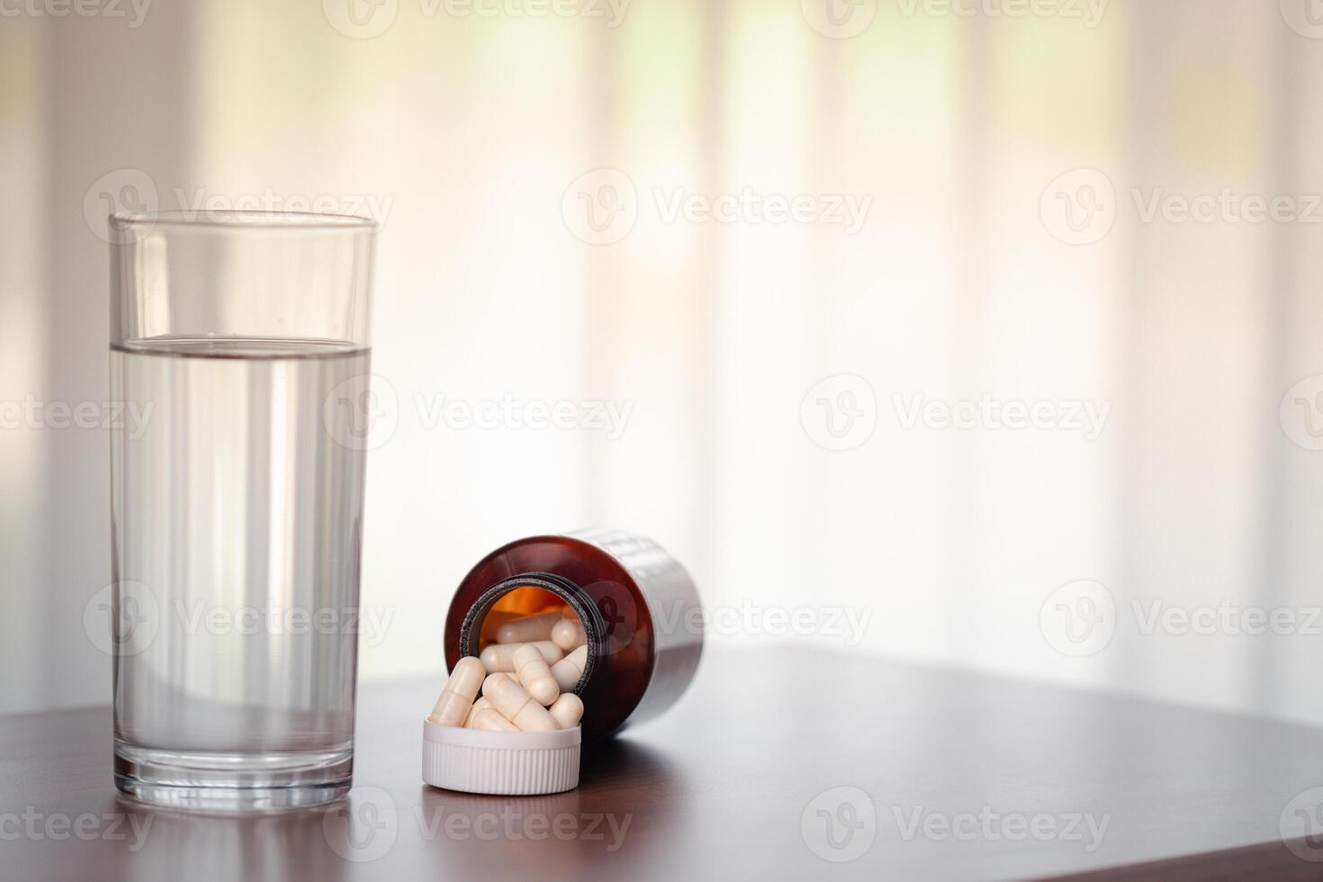 pilules et verre de l'eau sur en bois table dans le pièce photo