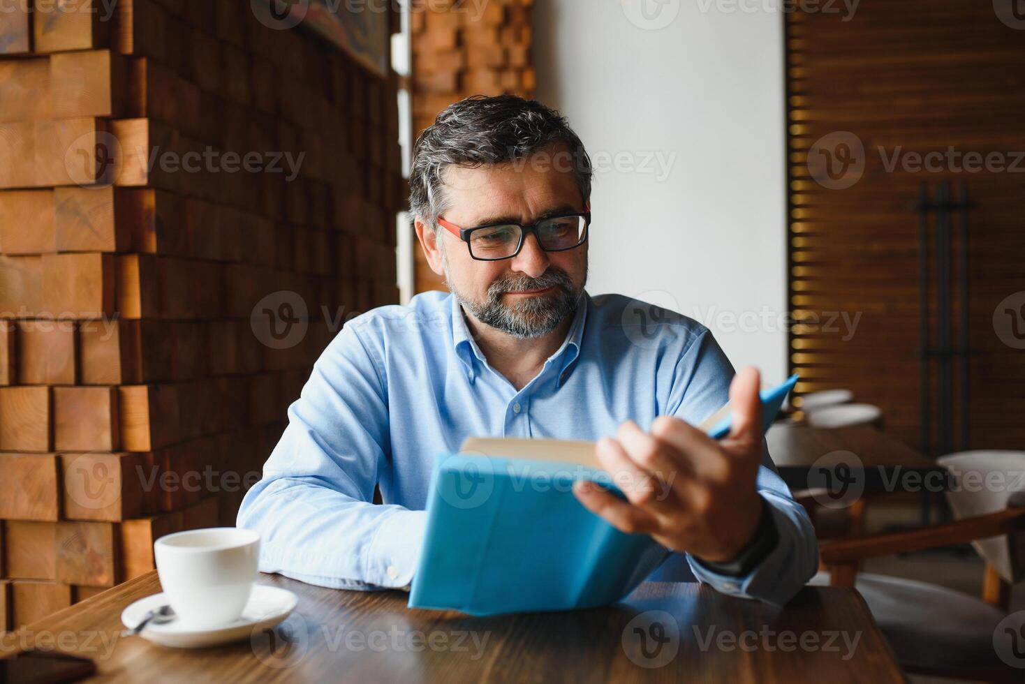 mature Beau homme en train de lire une livre dans une café photo