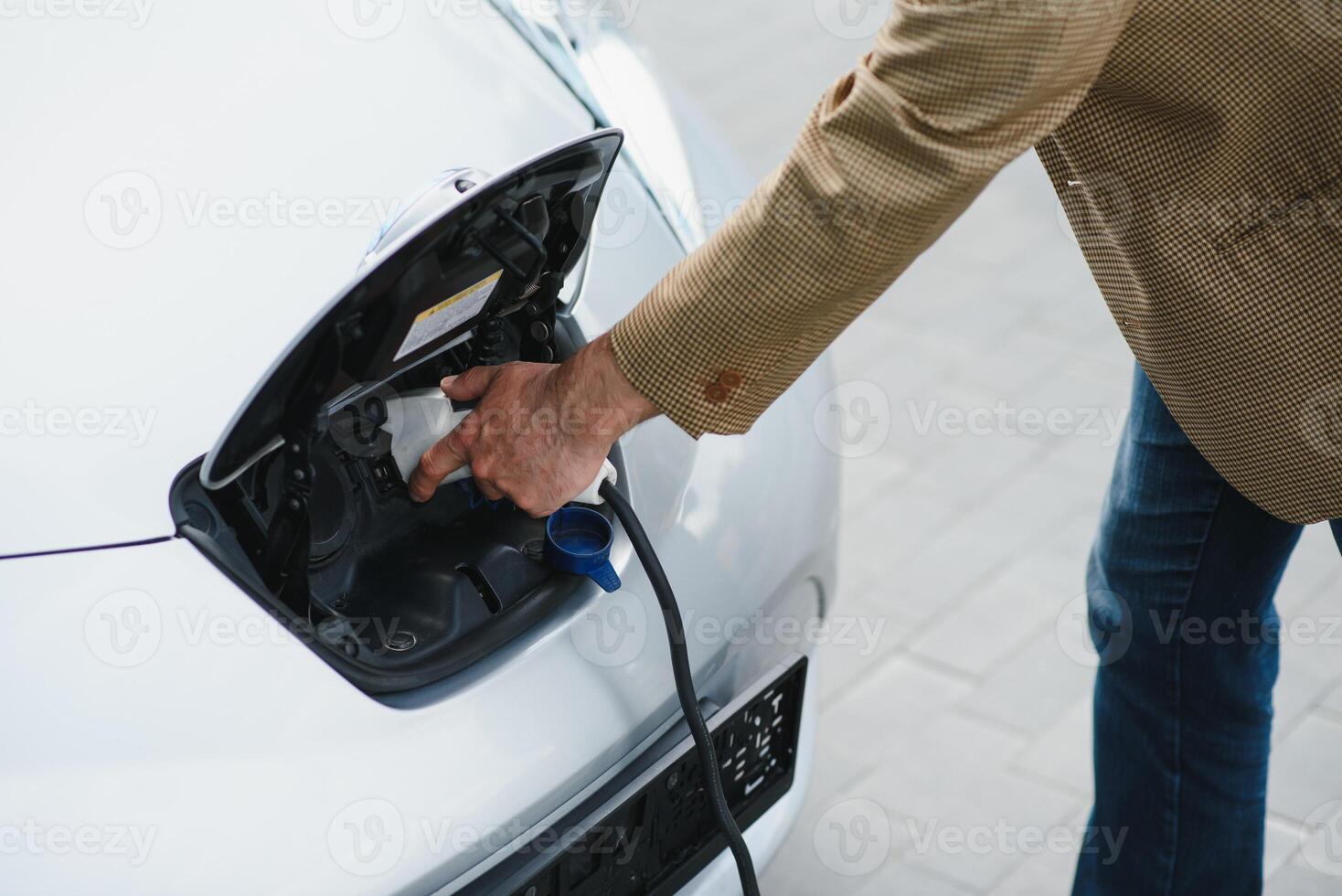 une homme d'affaire des charges un électrique voiture photo