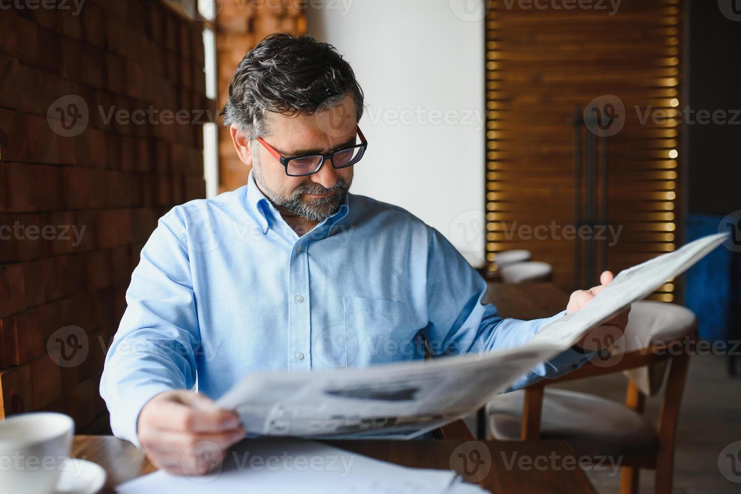 actif Sénior homme en train de lire journal et en buvant café dans restaurant photo