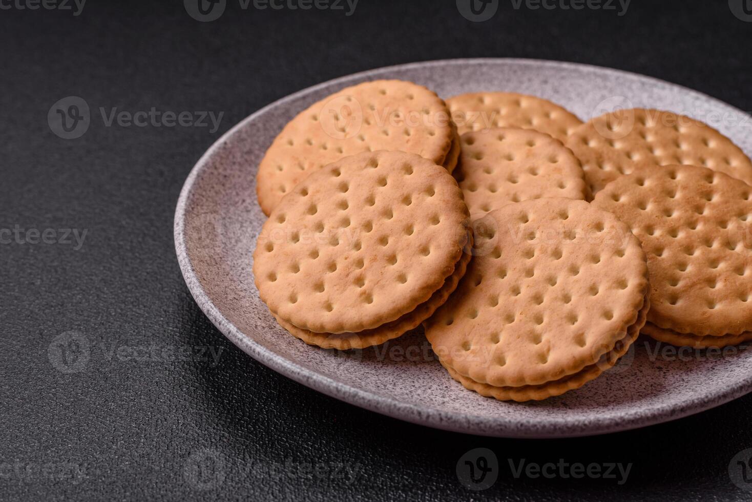 rond à pois casse-croûte casse-croûte biscuits avec crème sur une foncé béton Contexte photo