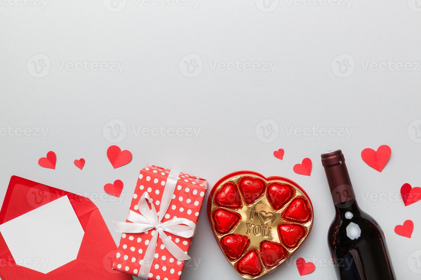 bouteille de rouge du vin sur coloré Contexte pour Valentin journée avec cadeau boîte, enveloppe et Chocolat. cœur en forme de avec cadeau boîte de des chocolats Haut vue avec copie espace photo