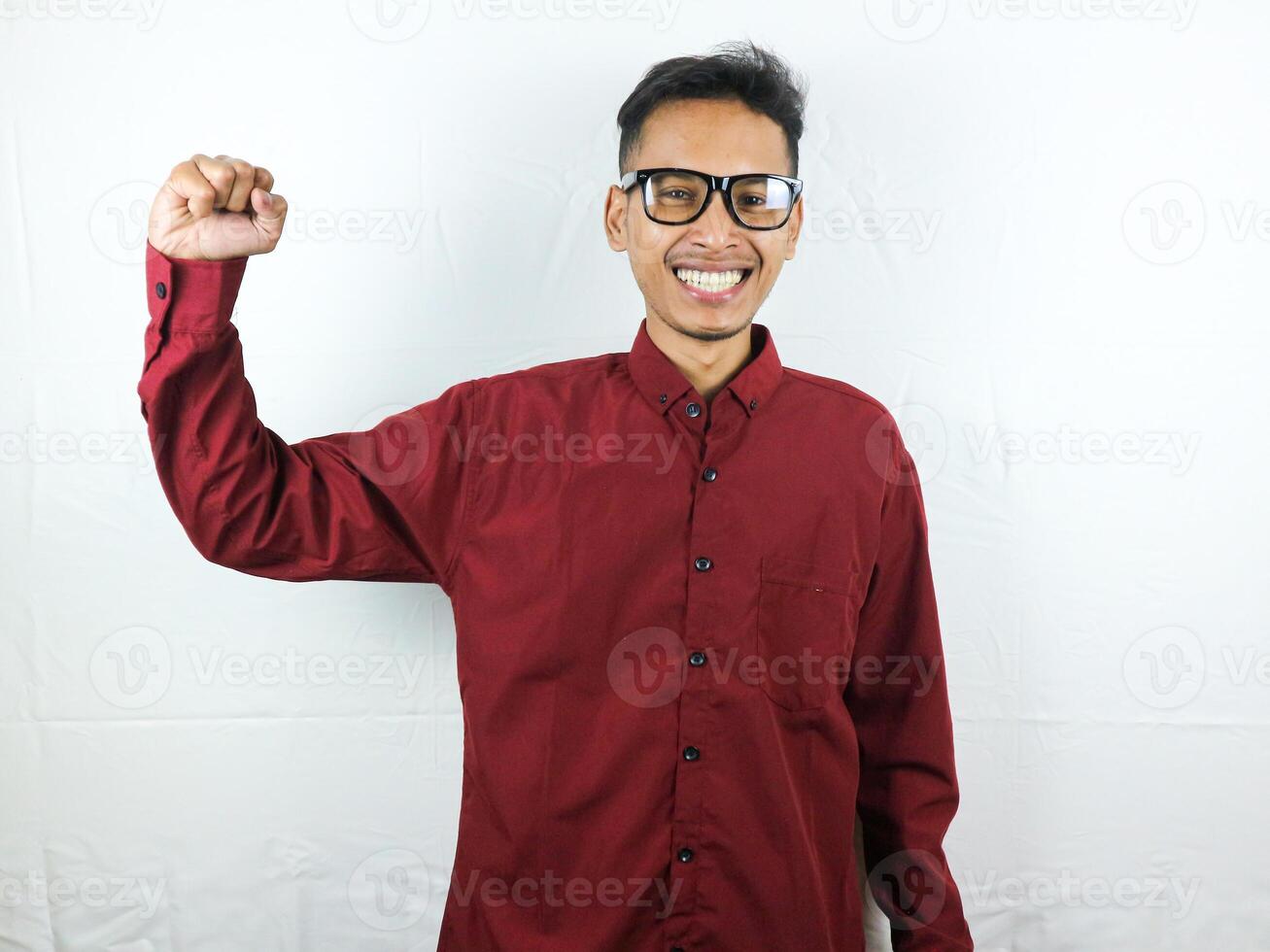 Beau homme dans des lunettes célébrer Succès avec serrant poing et content visage expression. photo