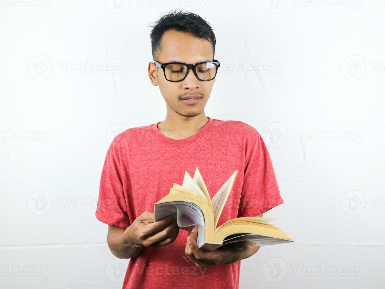 portrait de asiatique homme en portant livre avec en train de lire concentré expression. photo